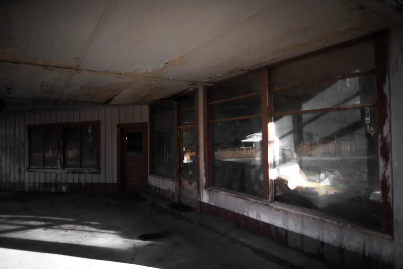 Sunlight falls through old windows onto the floor of an abandoned room.