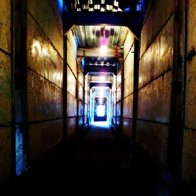 A narrow corridor glows with blue and gold light toward a distant doorway.