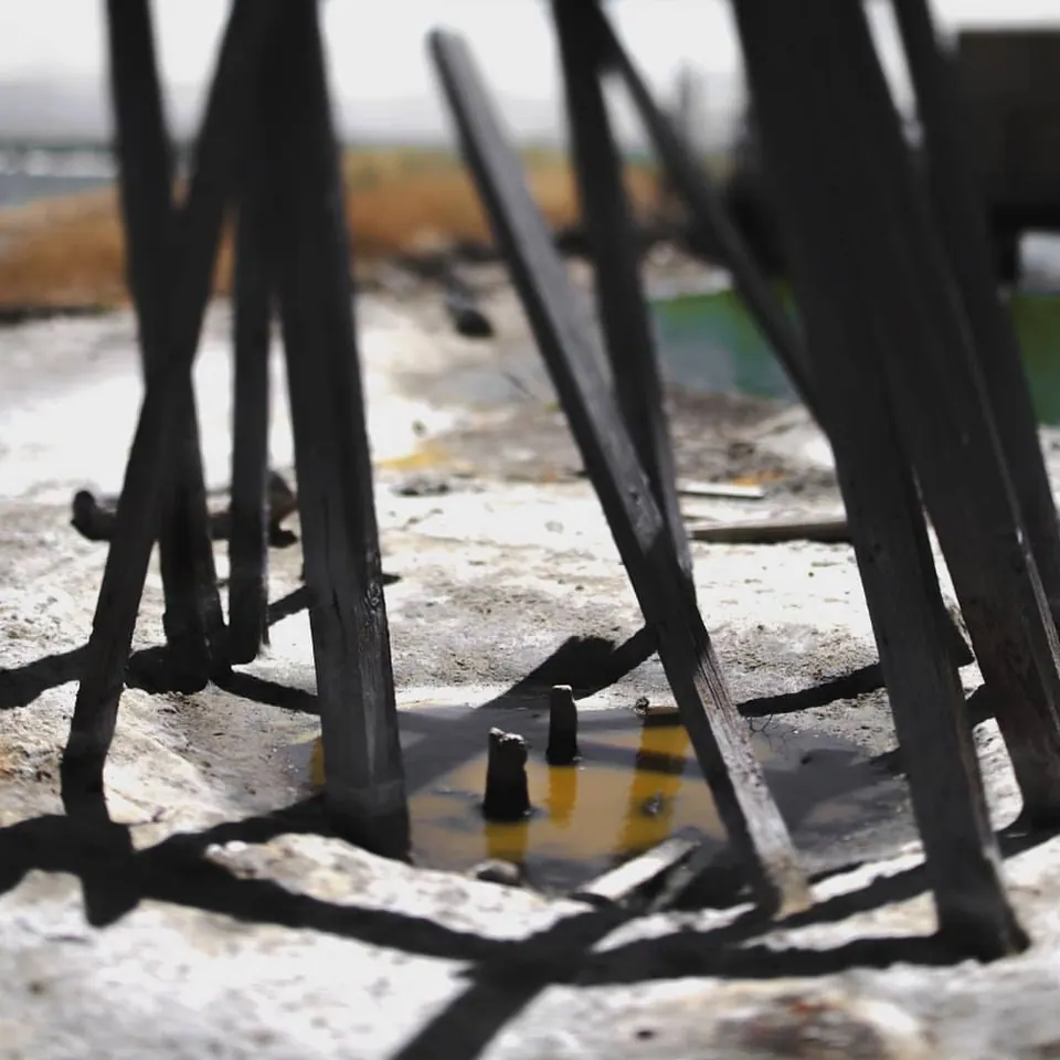 Thin dark metal forms cast long angular shadows across a pale surface.