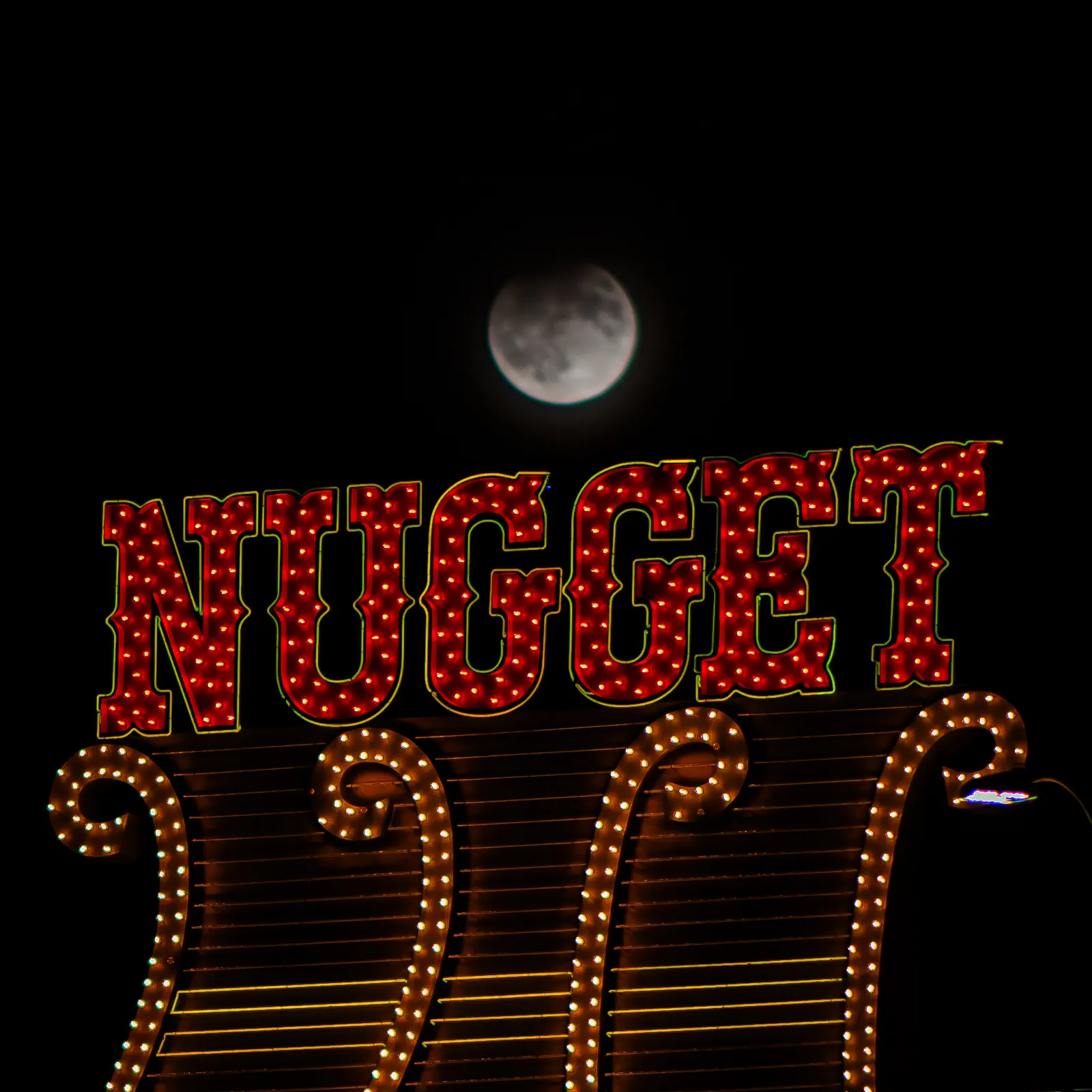 The moon hangs above red NUGGET lettering and rows of warm sign lights.