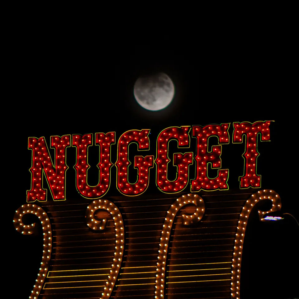 The moon hangs above red NUGGET lettering and rows of warm sign lights.