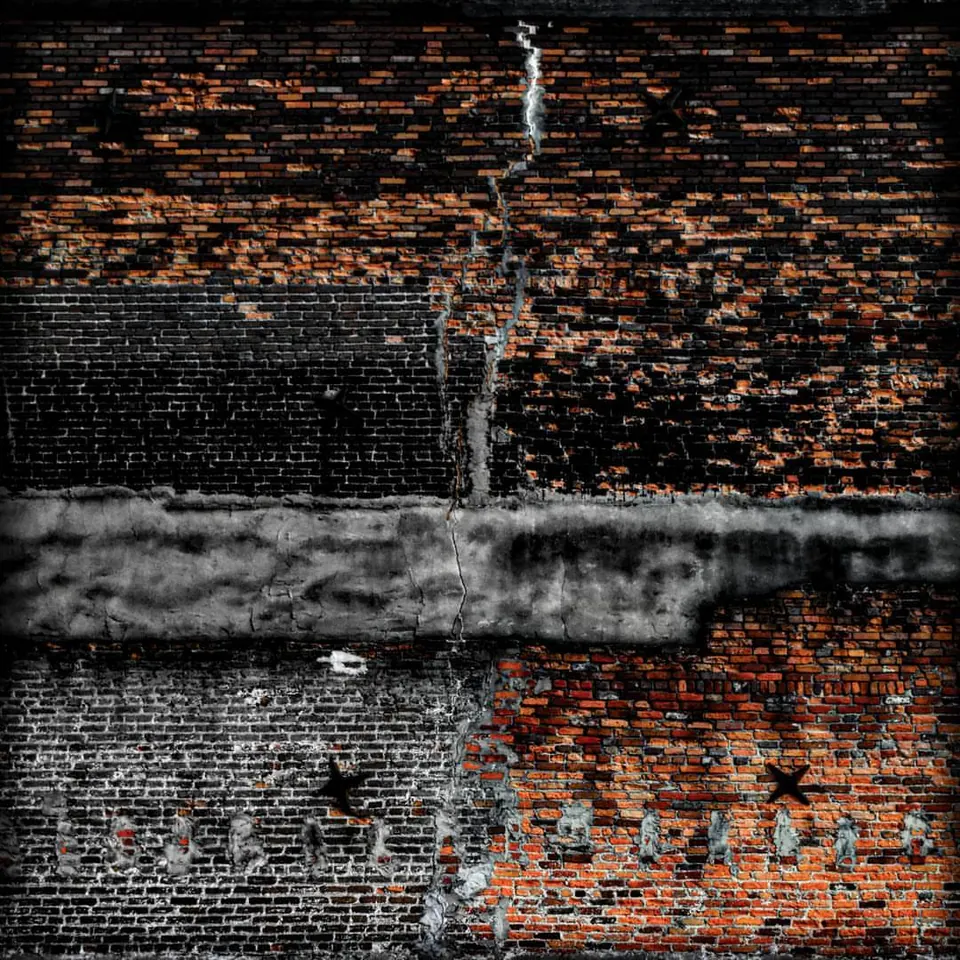 Warm brickwork rises above a dark, weathered wall.