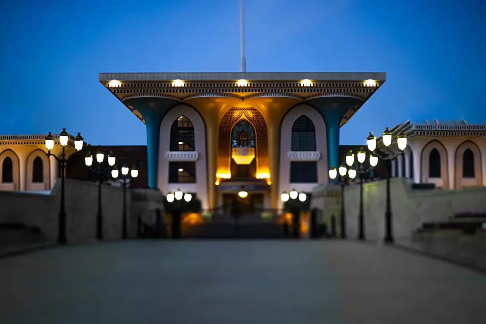 A brightly lit palace entrance stands beneath a deep blue evening sky.