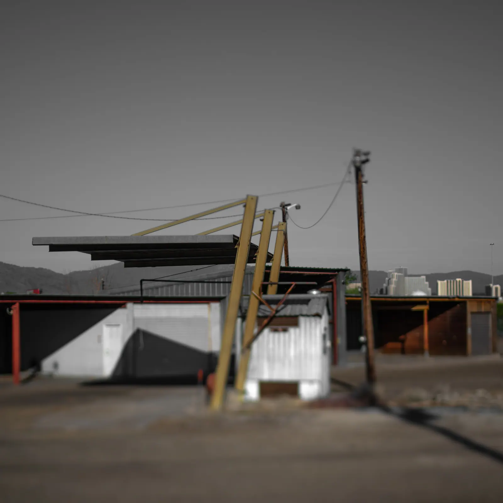 Utility poles and a small raised structure stand in an empty urban yard.