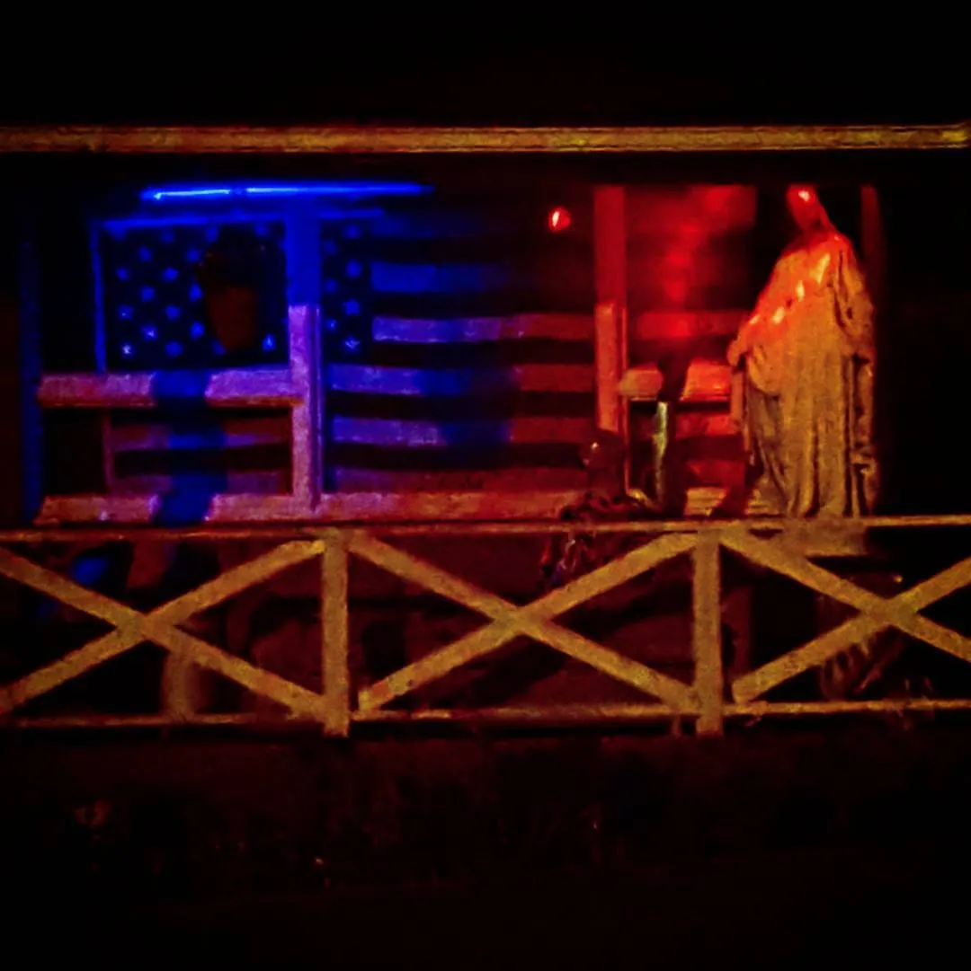 Red and blue lights illuminate a wooden porch and hanging decorations.