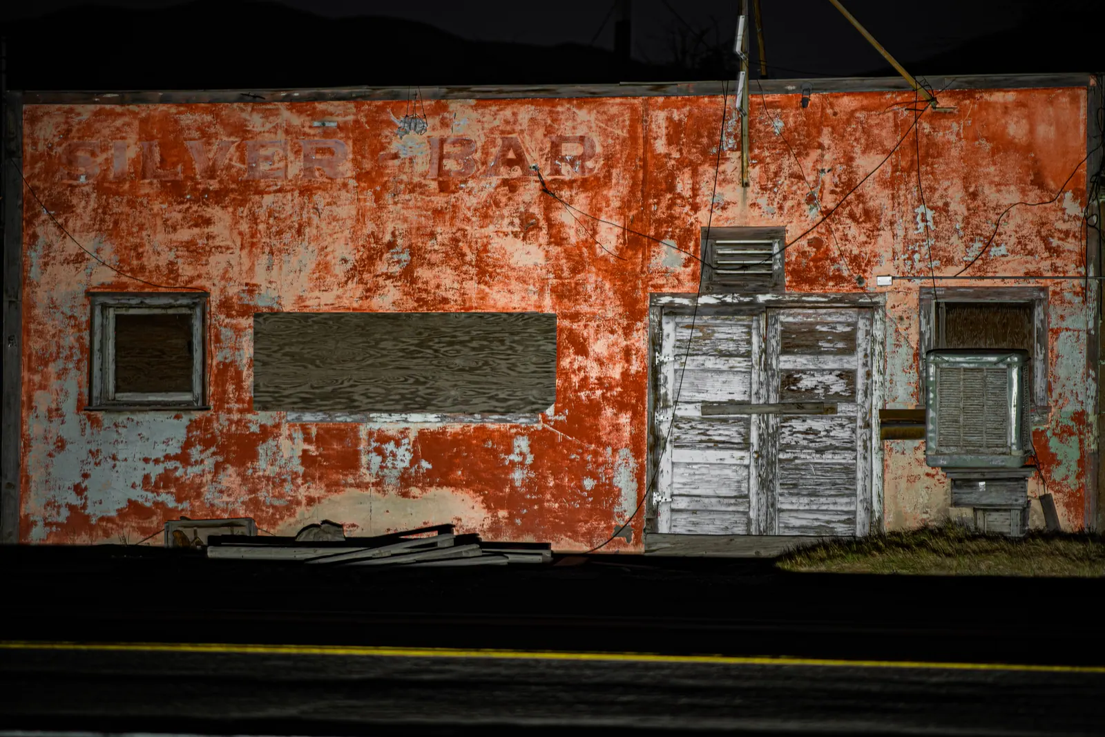 Peeling red paint and grey boarded doors form a weathered building facade.