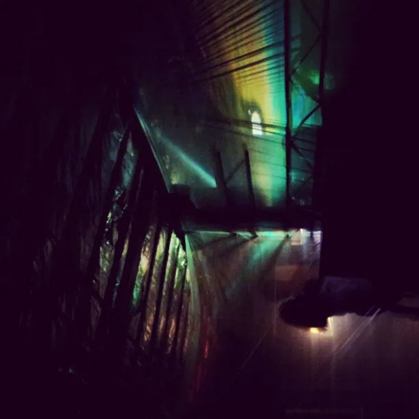 Green and violet reflections stretch along a narrow, dark interior passage.