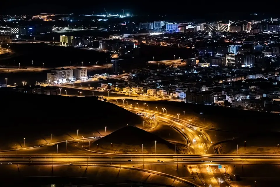 Illuminated roads curve around a hillside above a city at night.