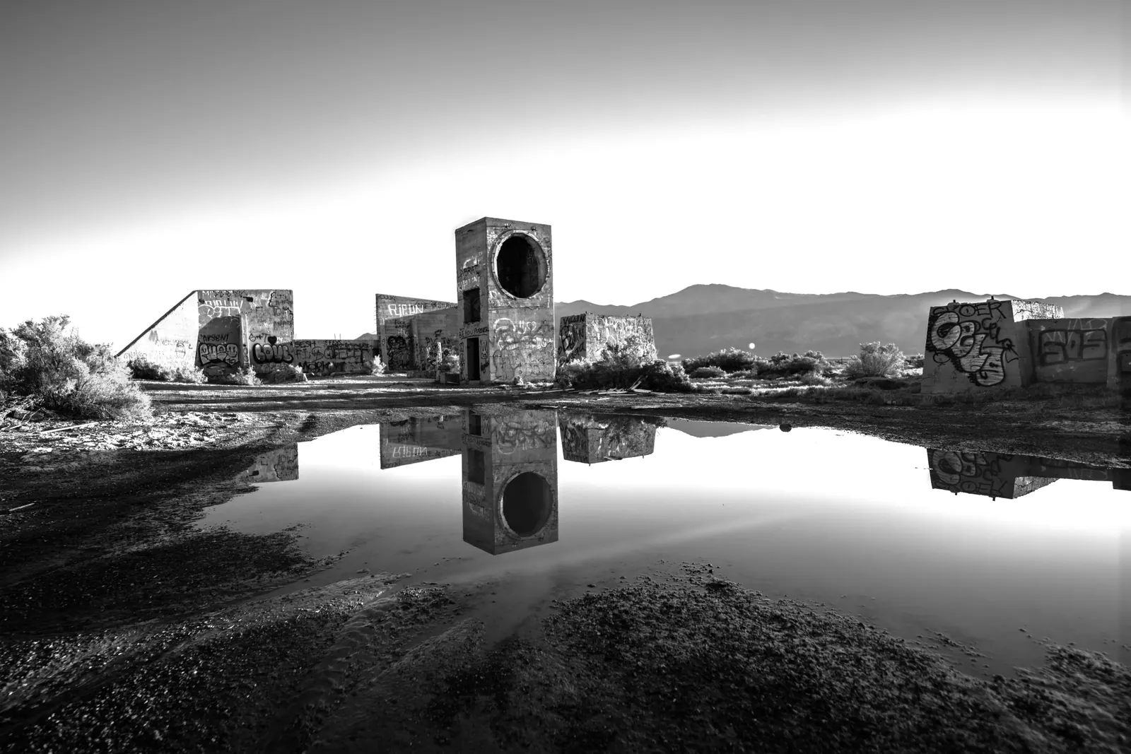 Broken stone walls and a small tower are mirrored in still water.