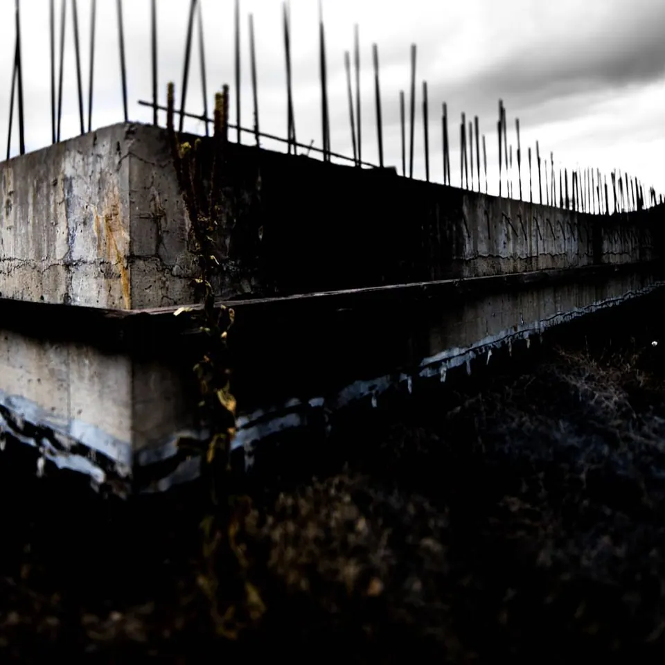 Rows of thin steel rods project from the edge of a rough concrete structure.