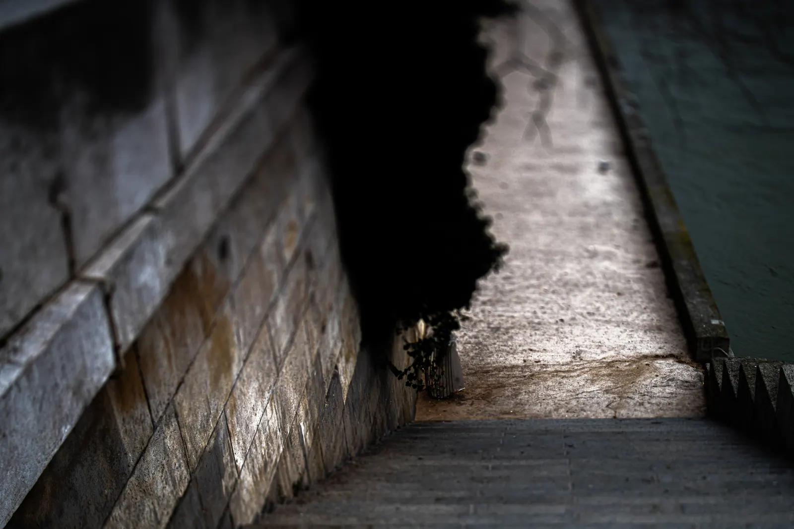 Stone steps descend beside a dark wall toward the water below.