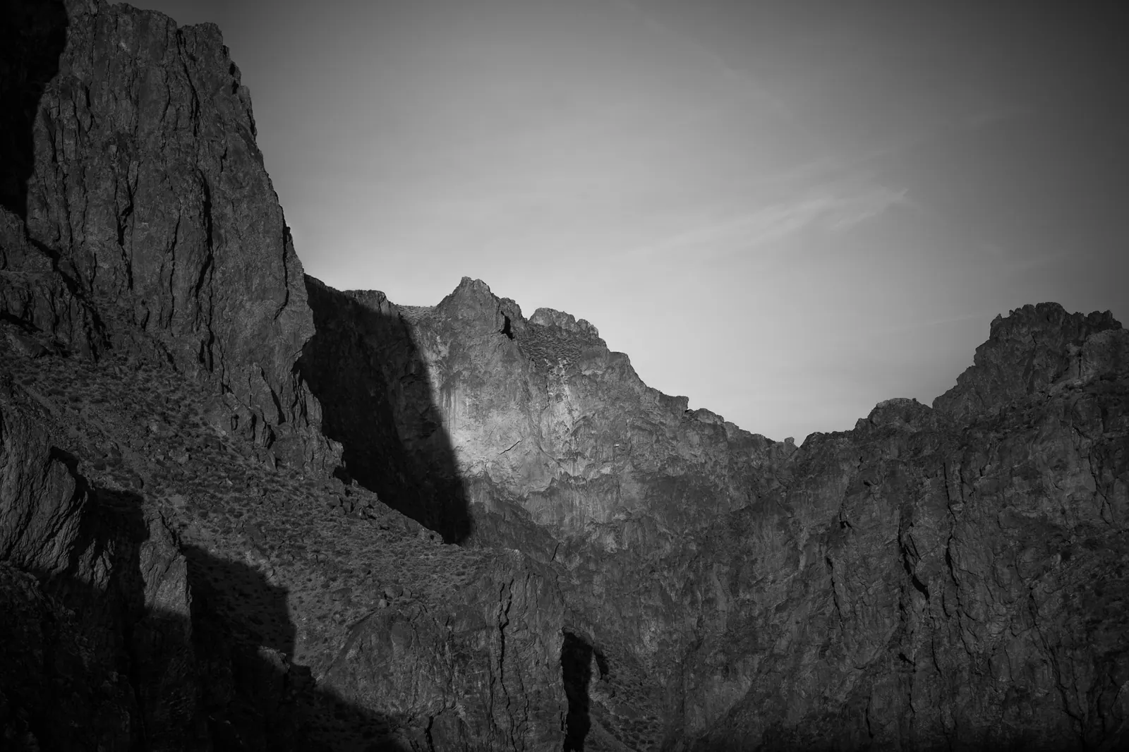 Steep, rugged rock walls frame a narrow gap beneath a soft grey sky.