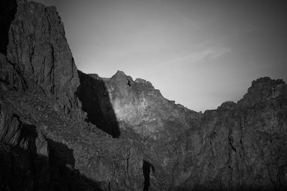 Steep, rugged rock walls frame a narrow gap beneath a soft grey sky.