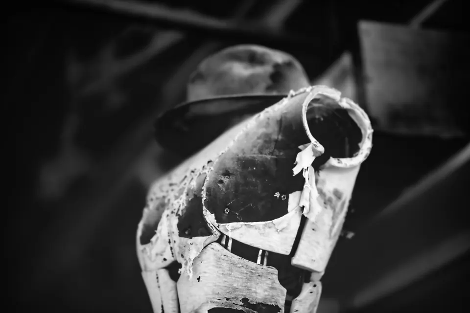 A dusty bottle with a torn label rests among the remains of an old building.