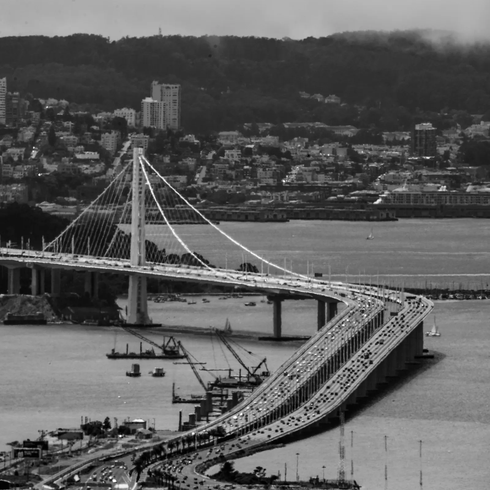 A long bridge curves across the water toward a densely built hillside.