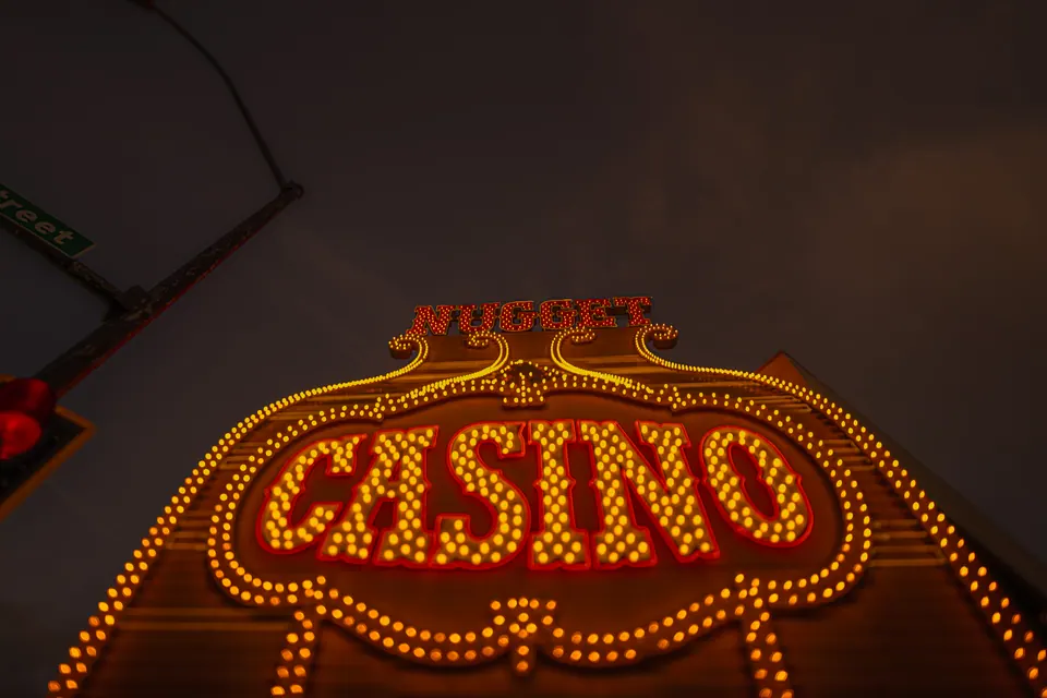 Warm bulbs outline a casino sign beneath a cloudy night sky.