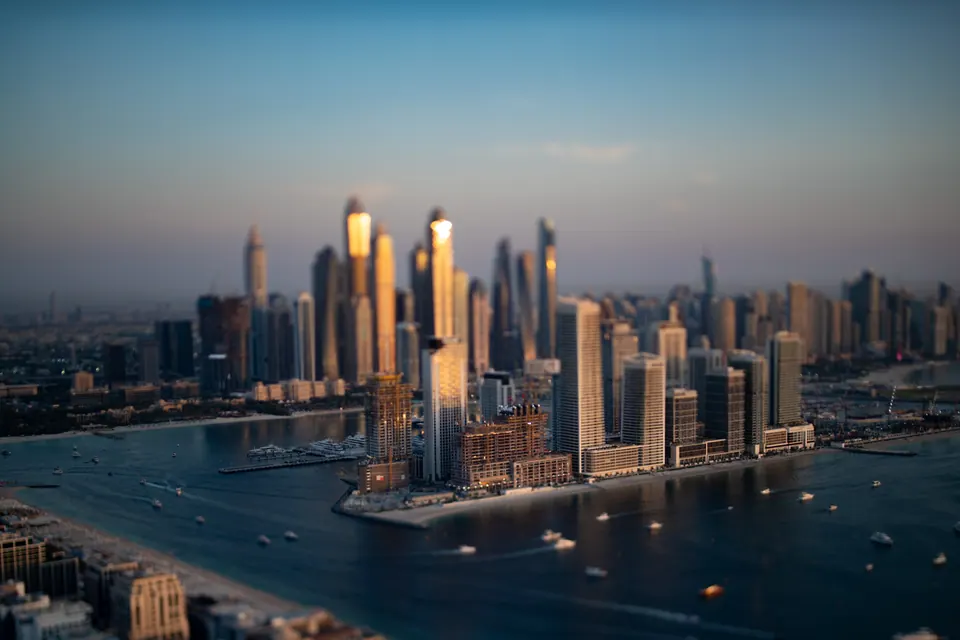 Tall buildings rise beside blue water in a wide view across Dubai.