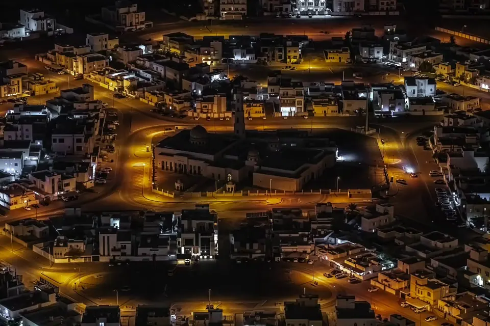 Golden streetlights thread through a dense city after dark.