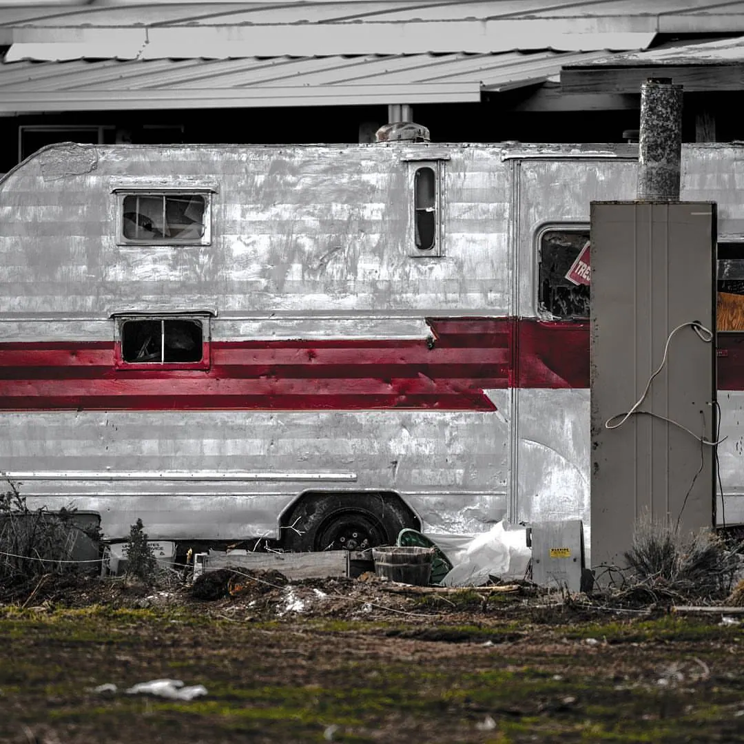 A worn red stripe crosses the side of an old trailer or vehicle.