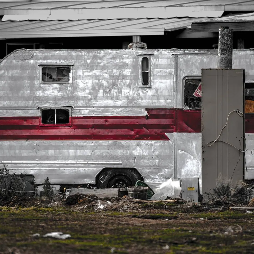 A worn red stripe crosses the side of an old trailer or vehicle.
