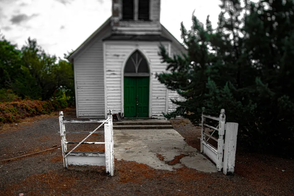 A green door brightens a small white church behind a low white fence.