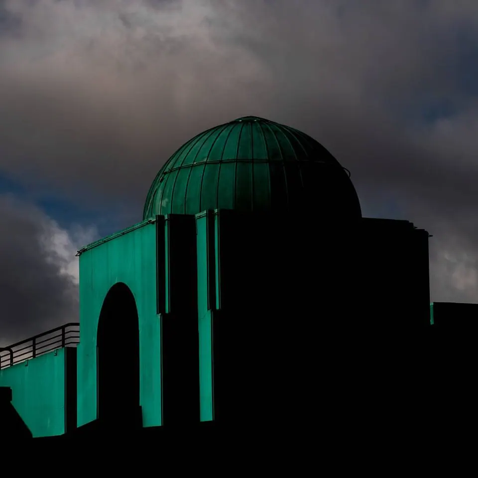 A green domed building rises beneath heavy grey clouds.