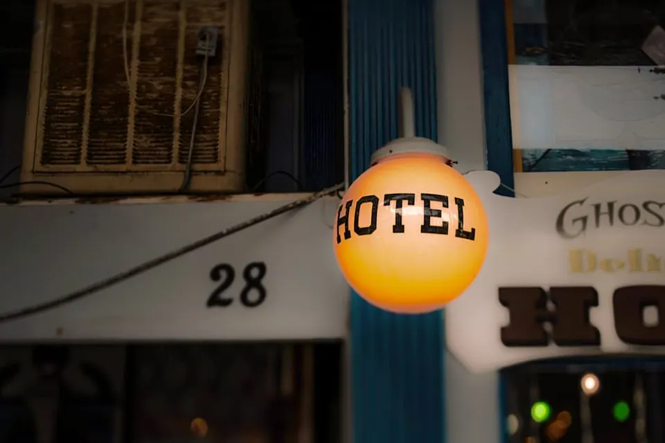 A round yellow hotel sign glows outside a shadowed building.