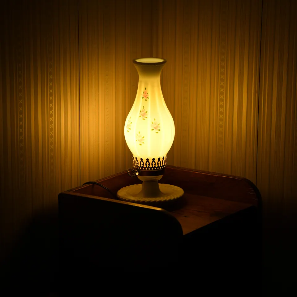 A small patterned lamp casts warm light across a table and wall.