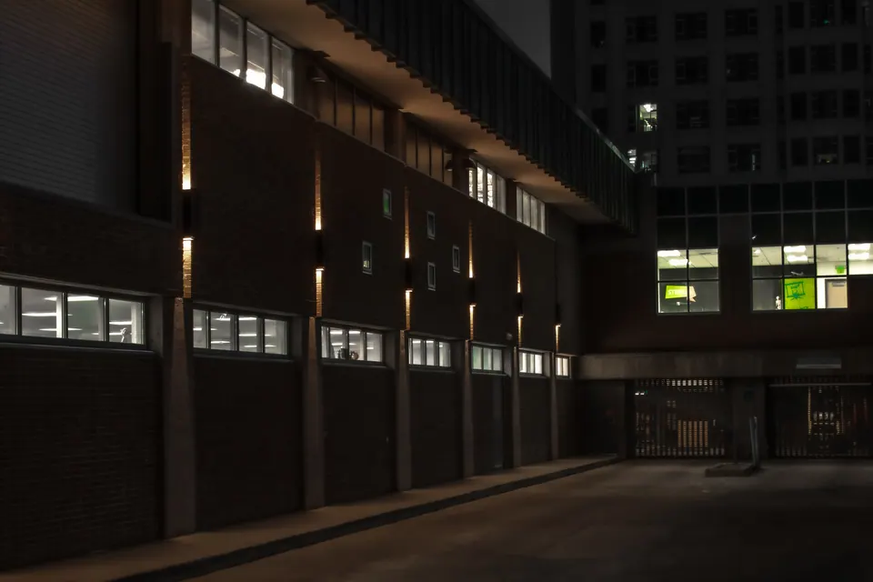 Lit windows punctuate the dark walls of an empty urban courtyard.