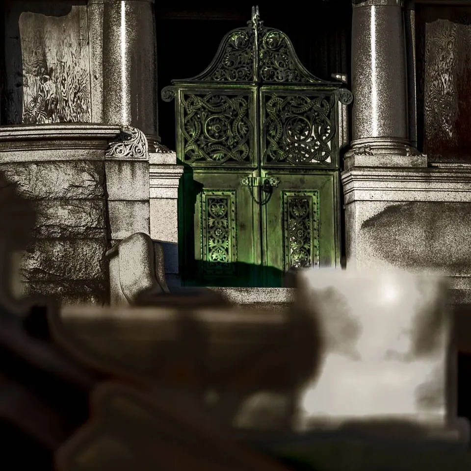 A decorative green metal gate stands within a pale stone entrance.