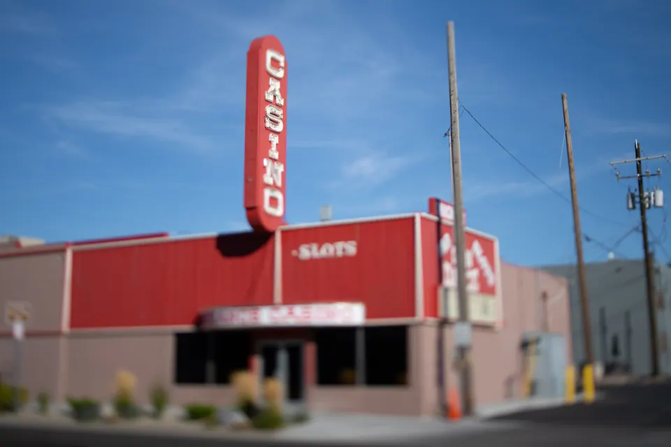 A red casino facade stands beside an empty street under a clear blue sky.