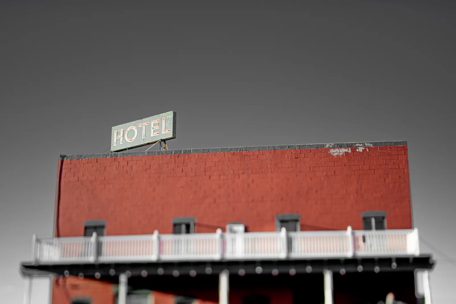 A simple hotel sign rises above a red brick facade beneath a pale sky.