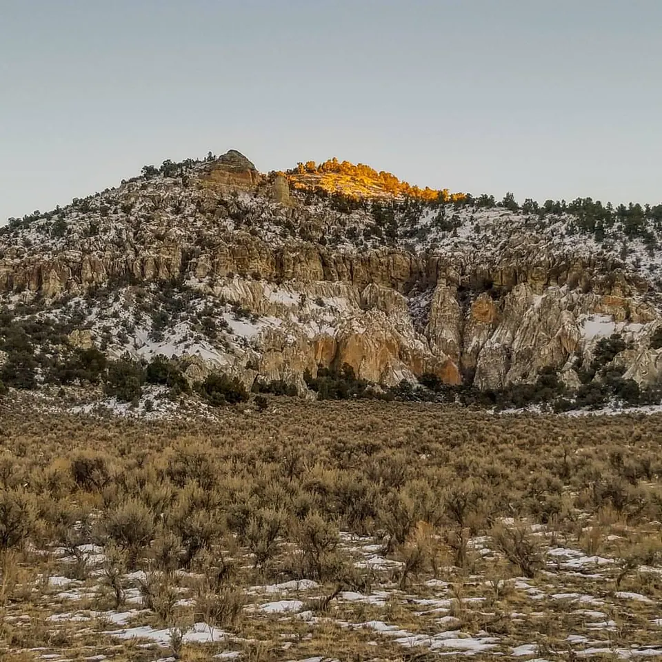 A snow-dusted hillside rises toward a small patch of warm light.