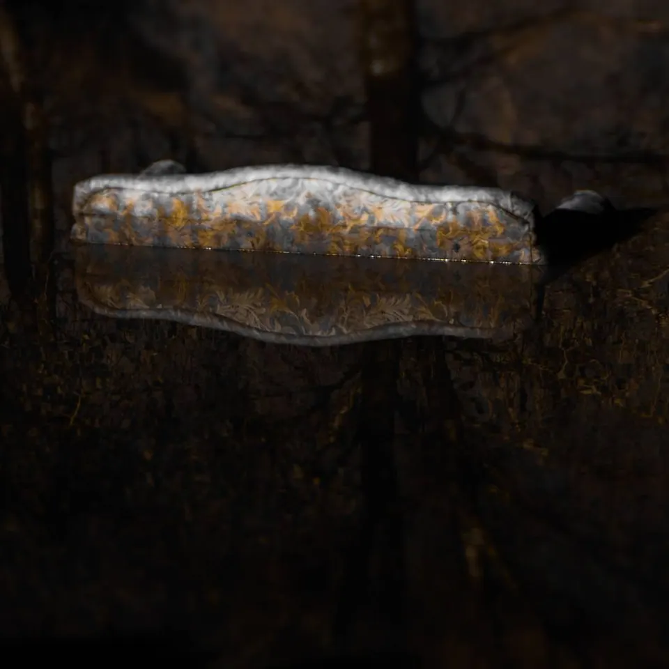 A weathered glass bottle lies against a dark, textured background.