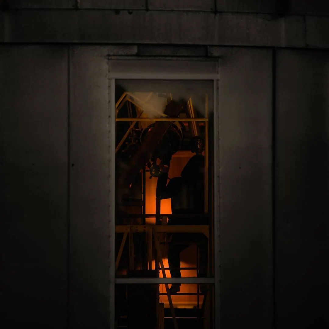 Warm orange light reveals a small interior through a narrow window.