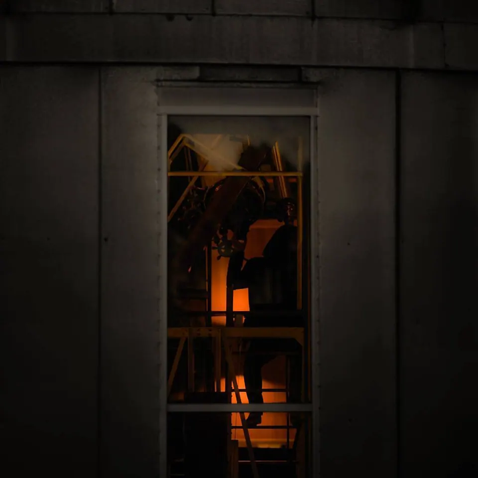 Warm orange light reveals a small interior through a narrow window.