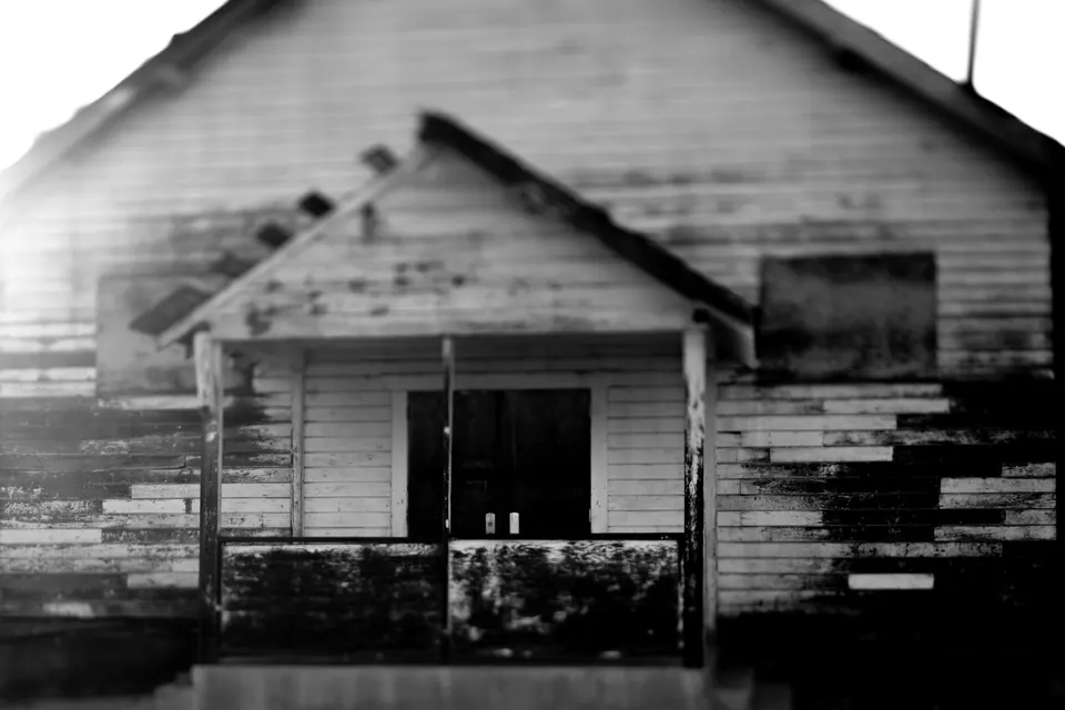 An empty doorway opens through the peeling facade of a wooden building.