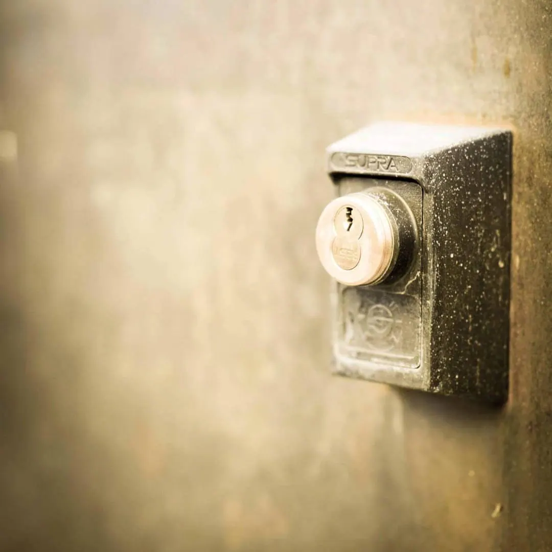 A small metal button projects from a weathered plate on a softly lit wall.