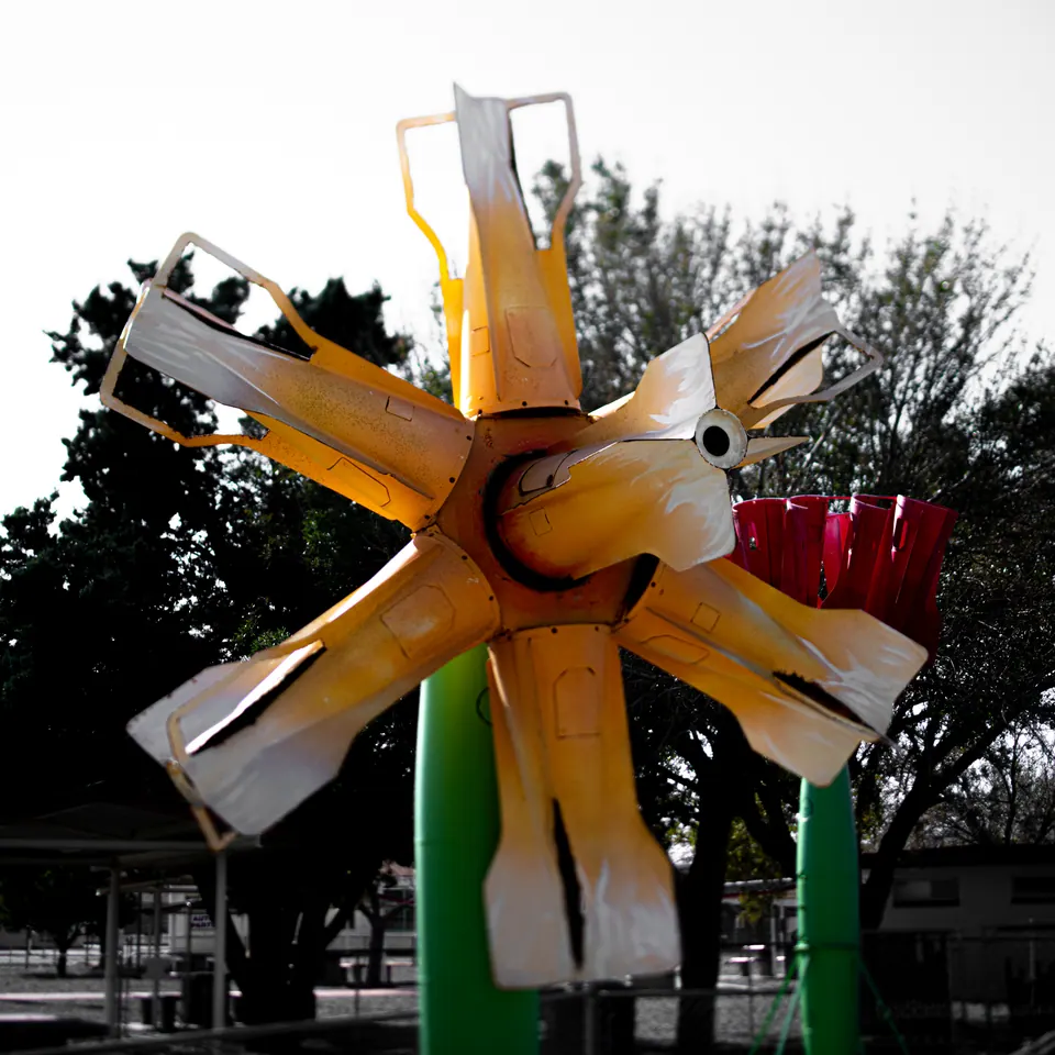 Yellow blades and red metal parts form a bright mechanical shape outdoors.