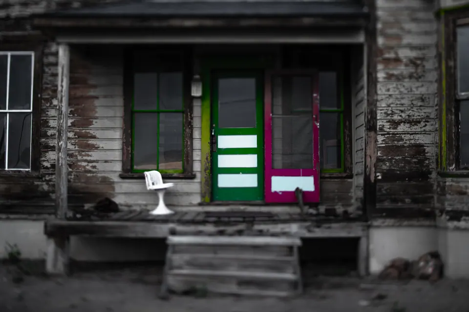 Green and purple doors add two small blocks of colour to a faded timber porch.