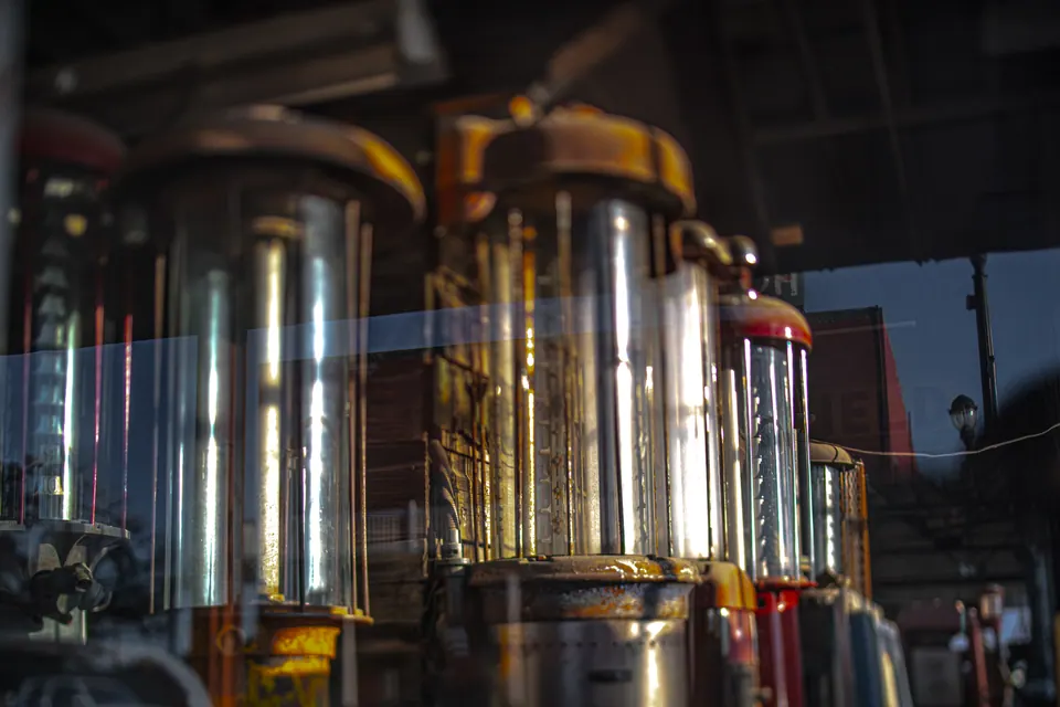 Warm reflections move across tall glass containers in a dim interior.