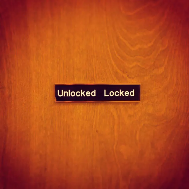 A small Unlocked Locked label sits on a warm wooden door.