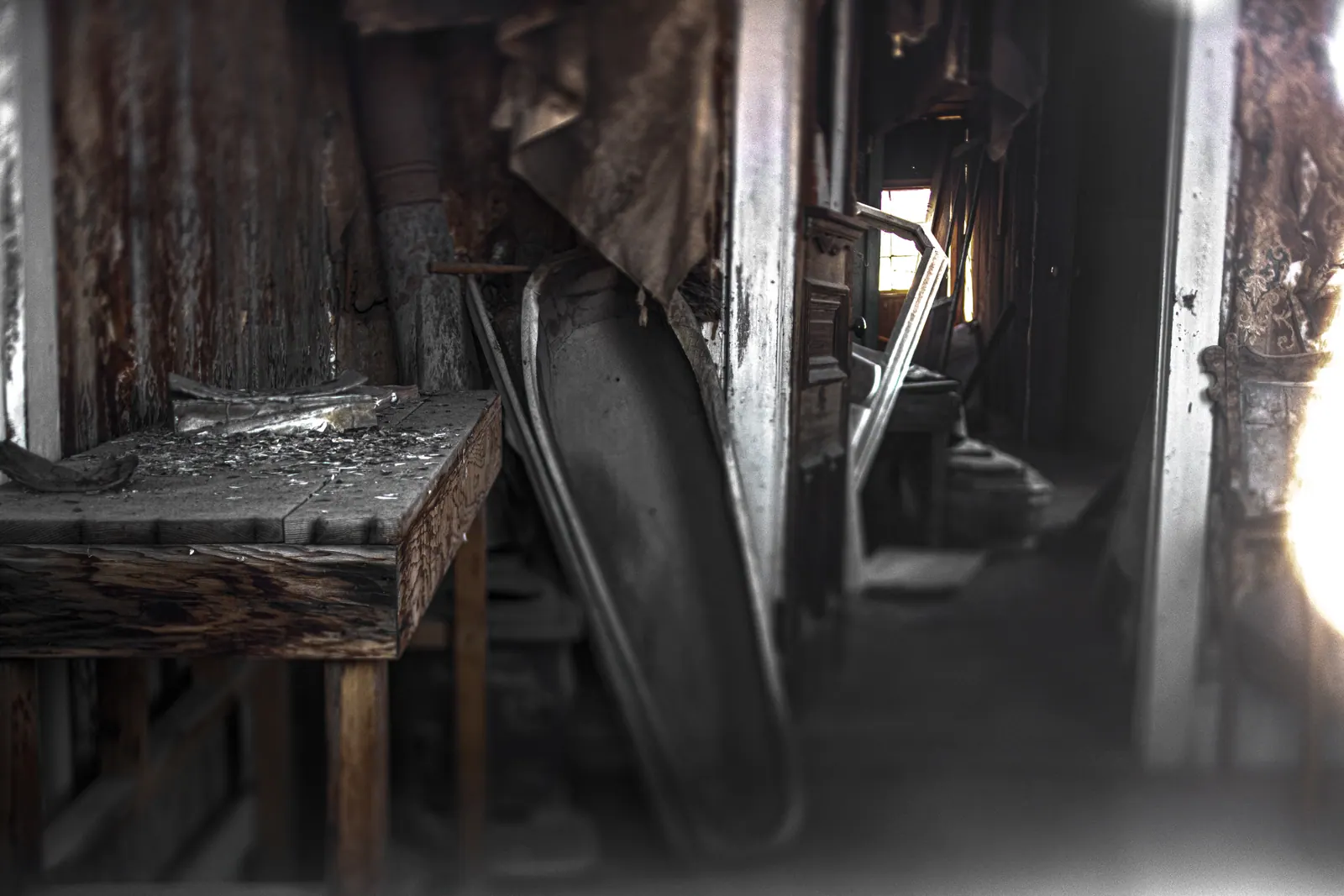 A curved wooden object rests beside a table in a dusty, half-lit room.