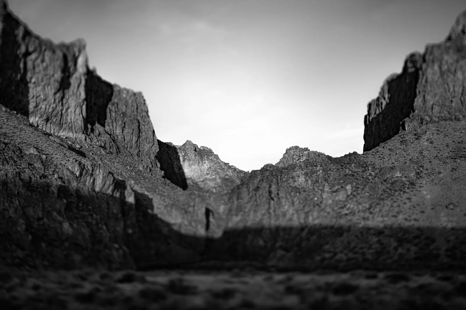 Rocky canyon walls recede toward a pale sky above a dark valley floor.